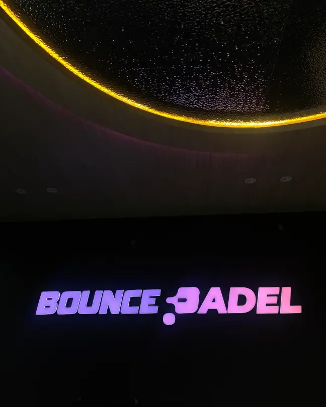 Bounce Padel neon sign under a starry ceiling